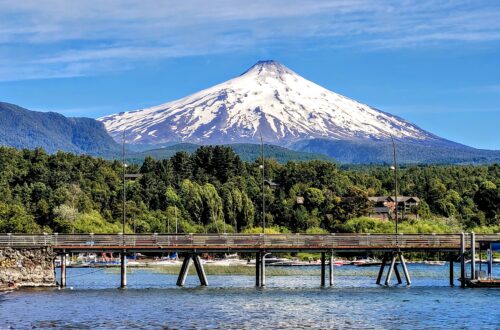 A view of a long pier on Villarrica Lake with the Villarrica volcano in the background; Pucon, Chile