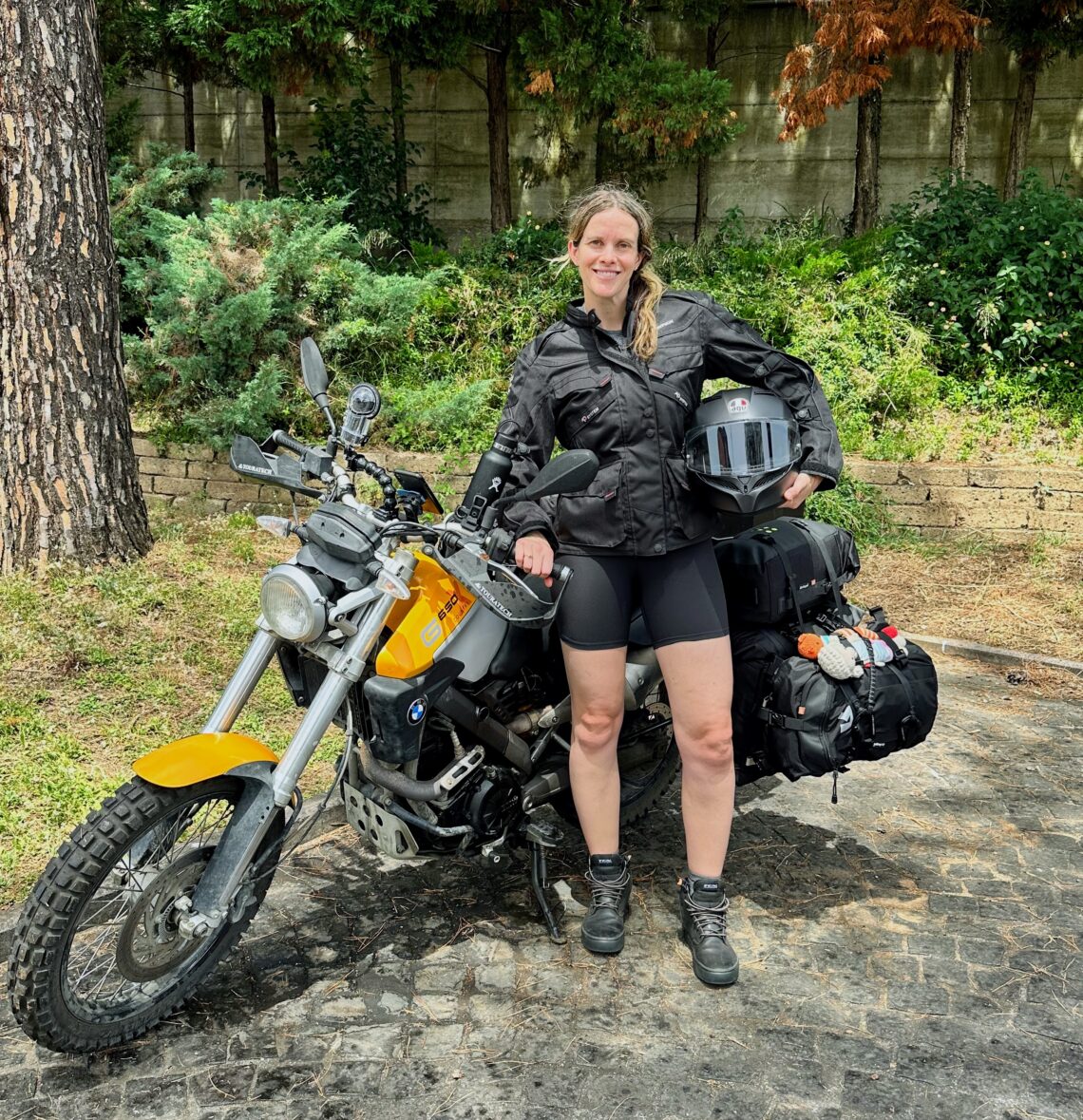 I'm standing in front of a BMW G650 motorcycle while holding my motorcycle helmet gearing up for our long motorcycle ride; Hotel Antonella, Pomezia (Italy)