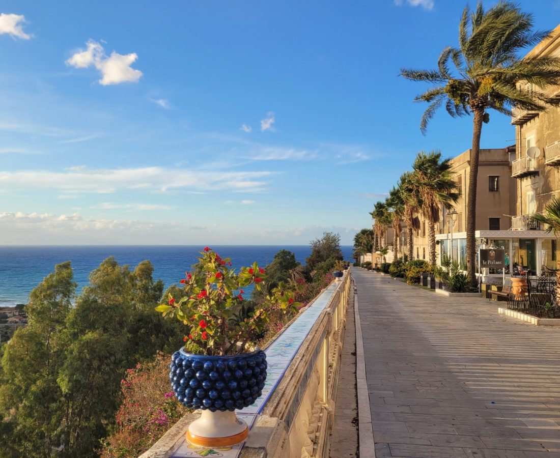 Blue ceramic pot resting on a long handrail leading to beautiful views of the Tyrrhenian Sea @ Belvedere di Porta Palermo; Santo Stefano di Camastra, Sicily (Italy)