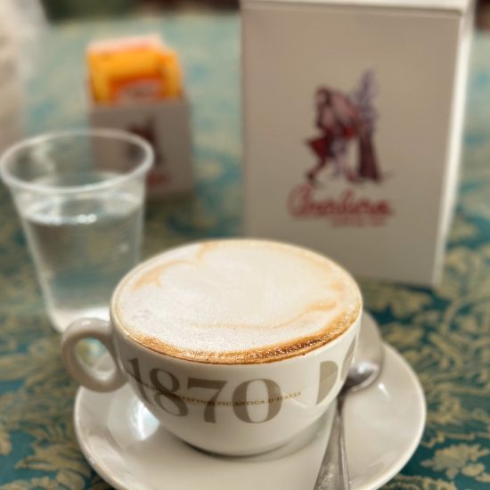 A cappuccino and a cup of water at Caprice espresso bar; Palazzolo Acreide, Sicily (Italy)