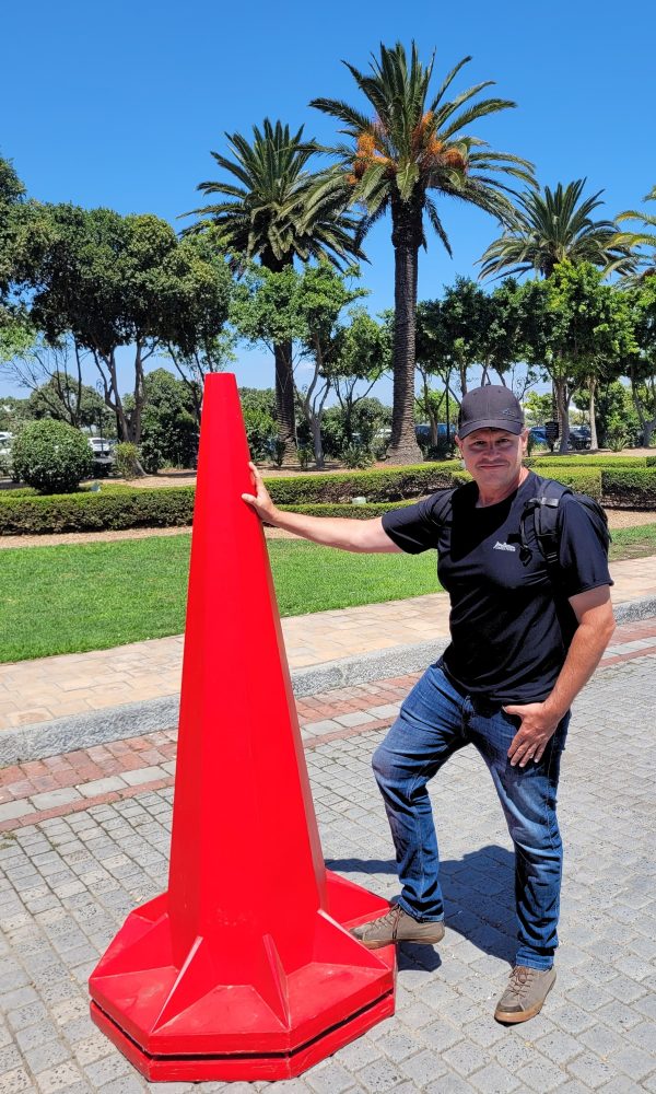 Paul is standing next to a 6 foot red pylon in the parking lot at Grand Hotel; Cape Town, South Africa