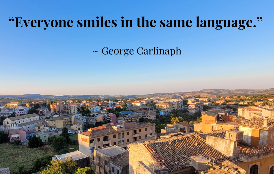 The sunsetting is casting a glow on the rooftops of the homes in the small Sicilian town, Palazzolo Acreide with the quote: "Everyone smiles in the same language." By: George Carlin; Palazzolo Acreide, Sicily (Italy)