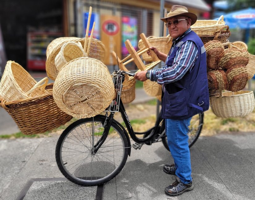 A local Chilean man balancing his bicycle with 20 handmade baskets hanging off of the sides; Pucón, Chile