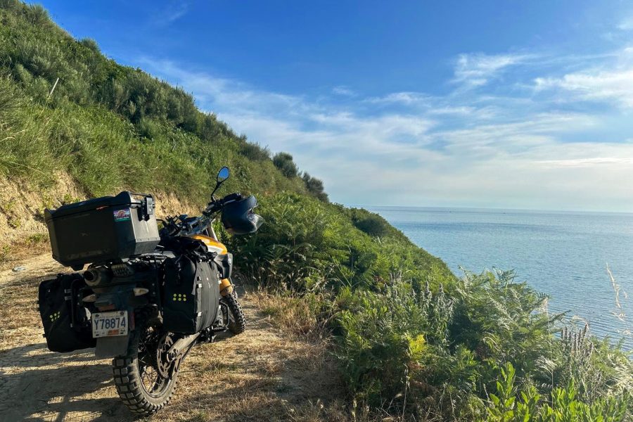 Our BMW G650 X Country motorcycle off to the left side with a steep cliff on the other side overlooking the Adriatic Sea; Durres, Albania